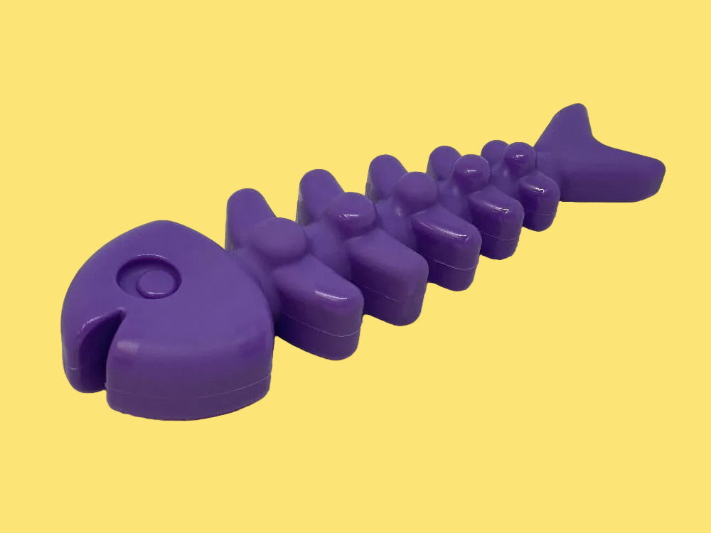 Purple dog toy shaped like a fish on a white background