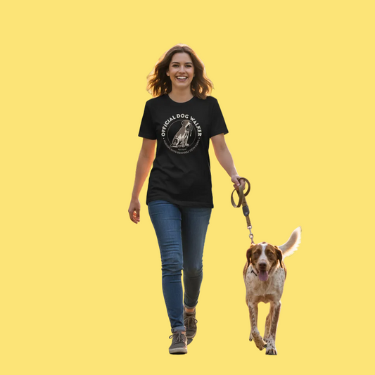 Woman walking a dog on a yellow background wearing a black t-shirt with a graphic design.