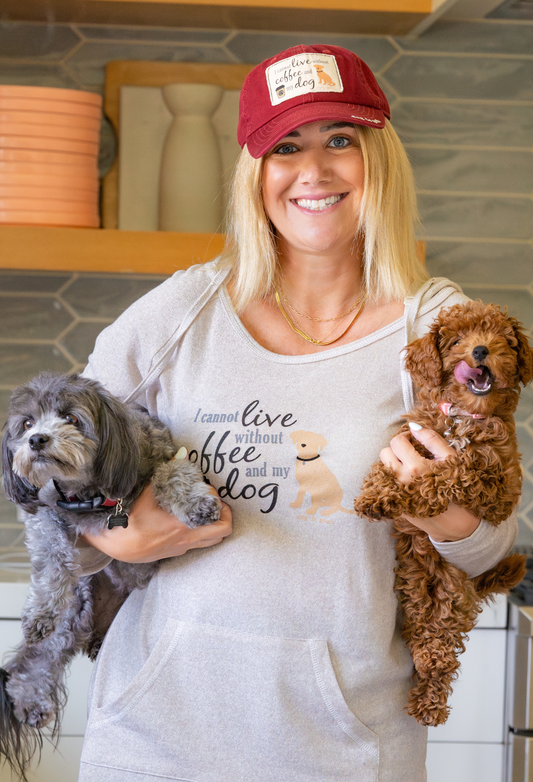 Woman holding two dogs, one gray and one brown, in a kitchen setting.